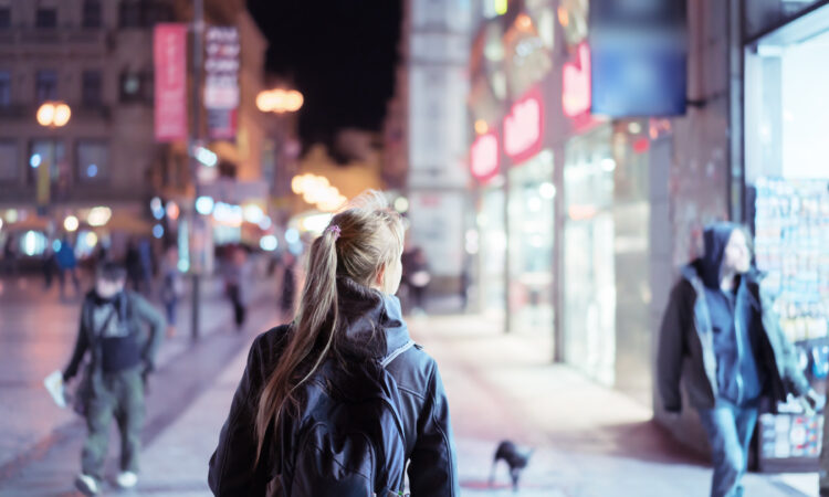 How safe is your neighborhood? Girl walking alone down a street at night.